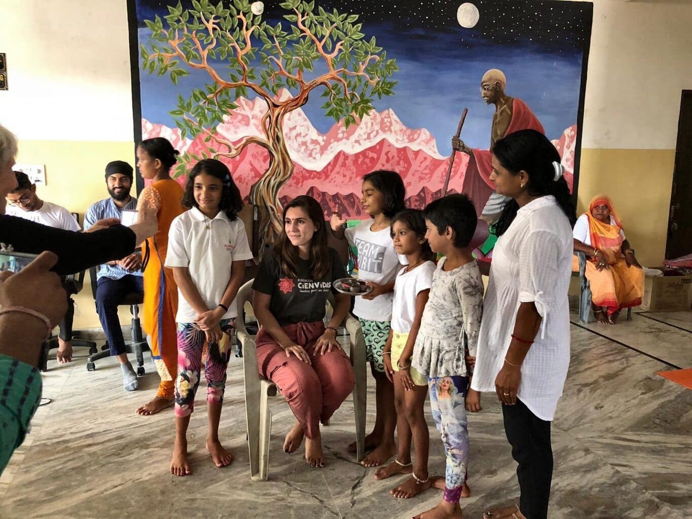 Fondo mural en centro de convivencia con niños, adultos y voluntarios en proyecto social de Fundación Cienvidas en India.