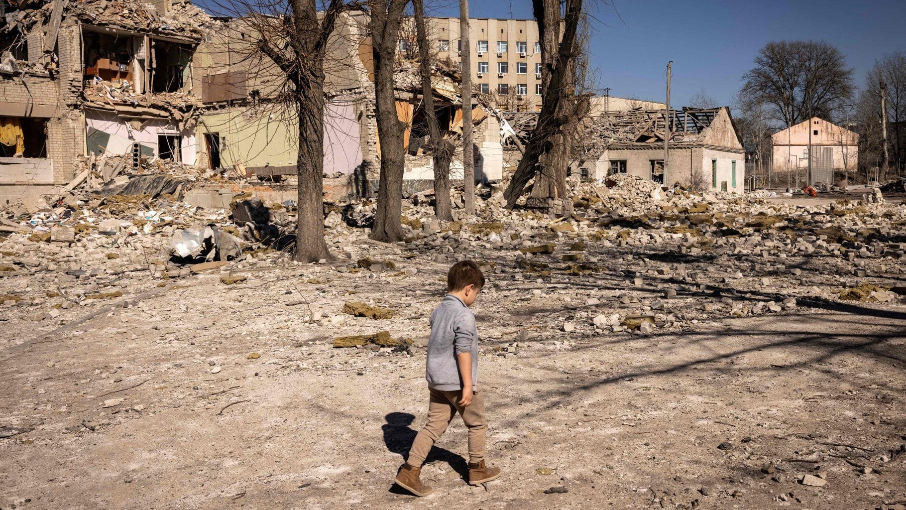 Mu niño caminando por un paisaje de destrucción y daños en un entorno urbano destruido.