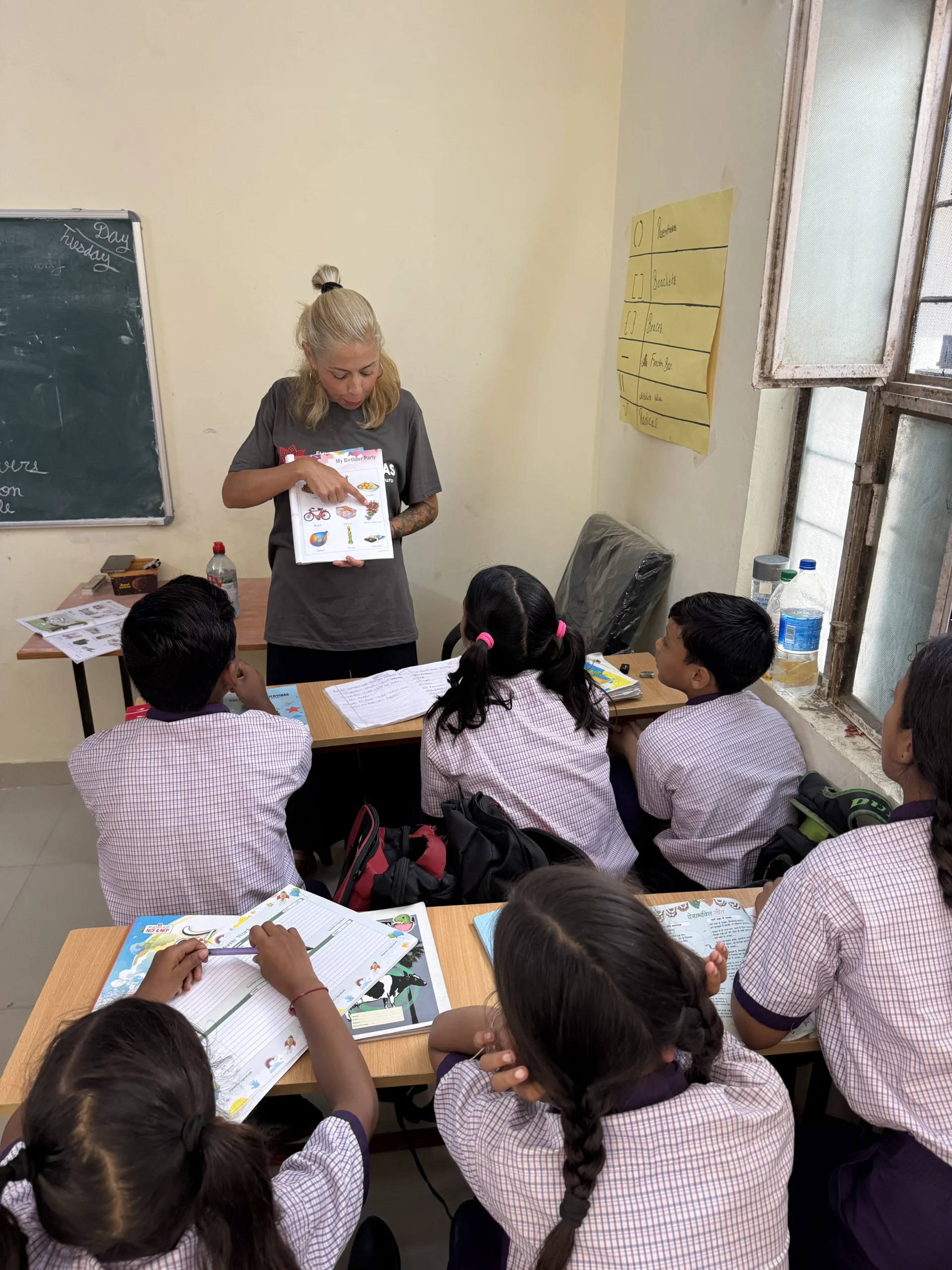 Voluntaria usando un libro ilustrado en actividad de inglés con niños en Jaipur, India