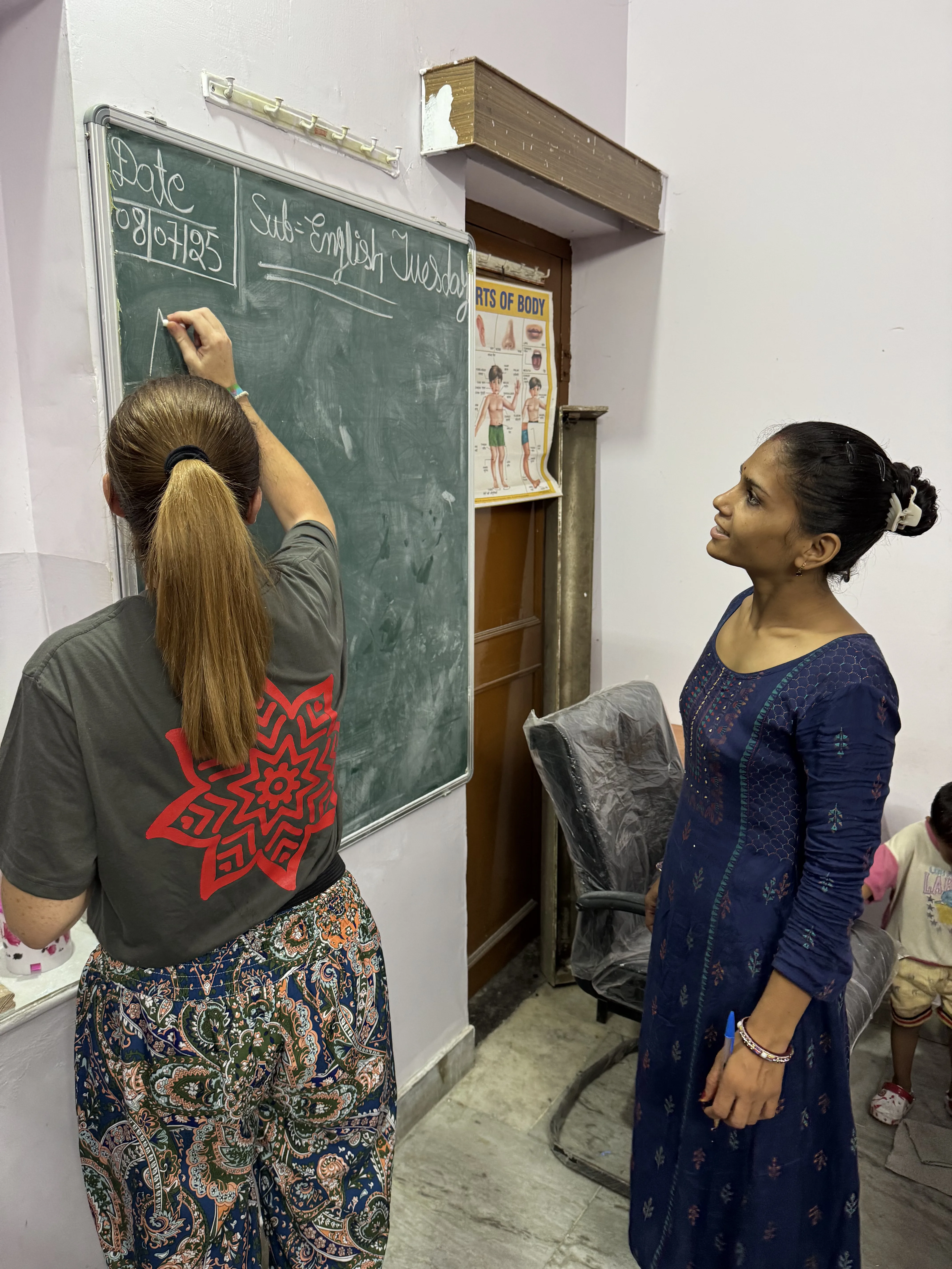 Voluntaria junto a profesora local explicando inglés en la pizarra en Jaipur, India