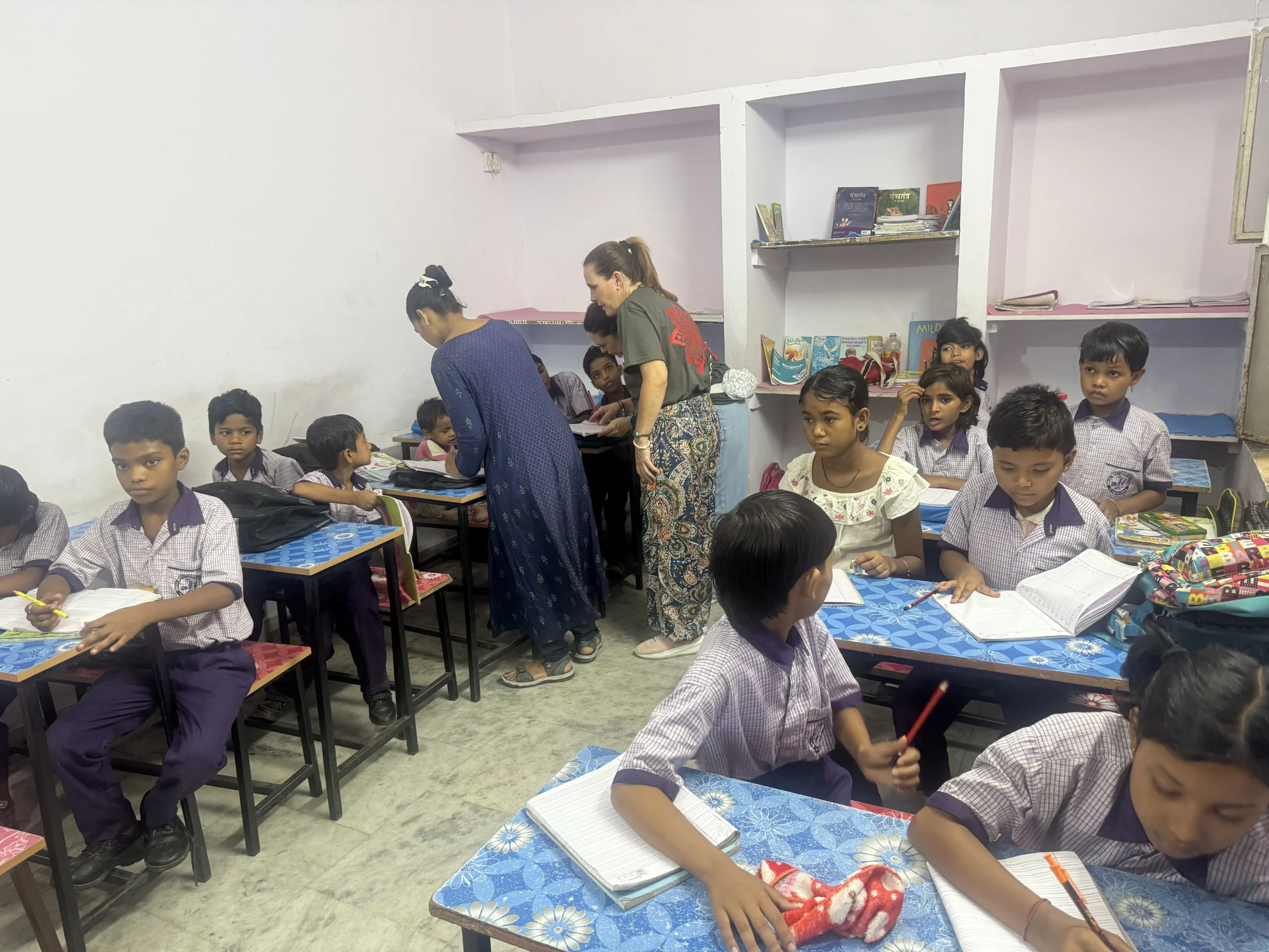 Voluntaria y profesora local ayudando a alumnos con sus cuadernos en Jaipur, India
