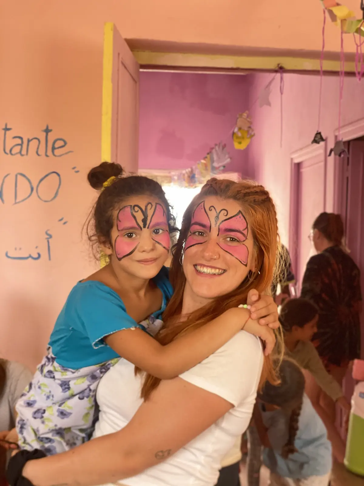 Voluntaria y niña durante una actividad de pintacaras del programa Manos que Unen