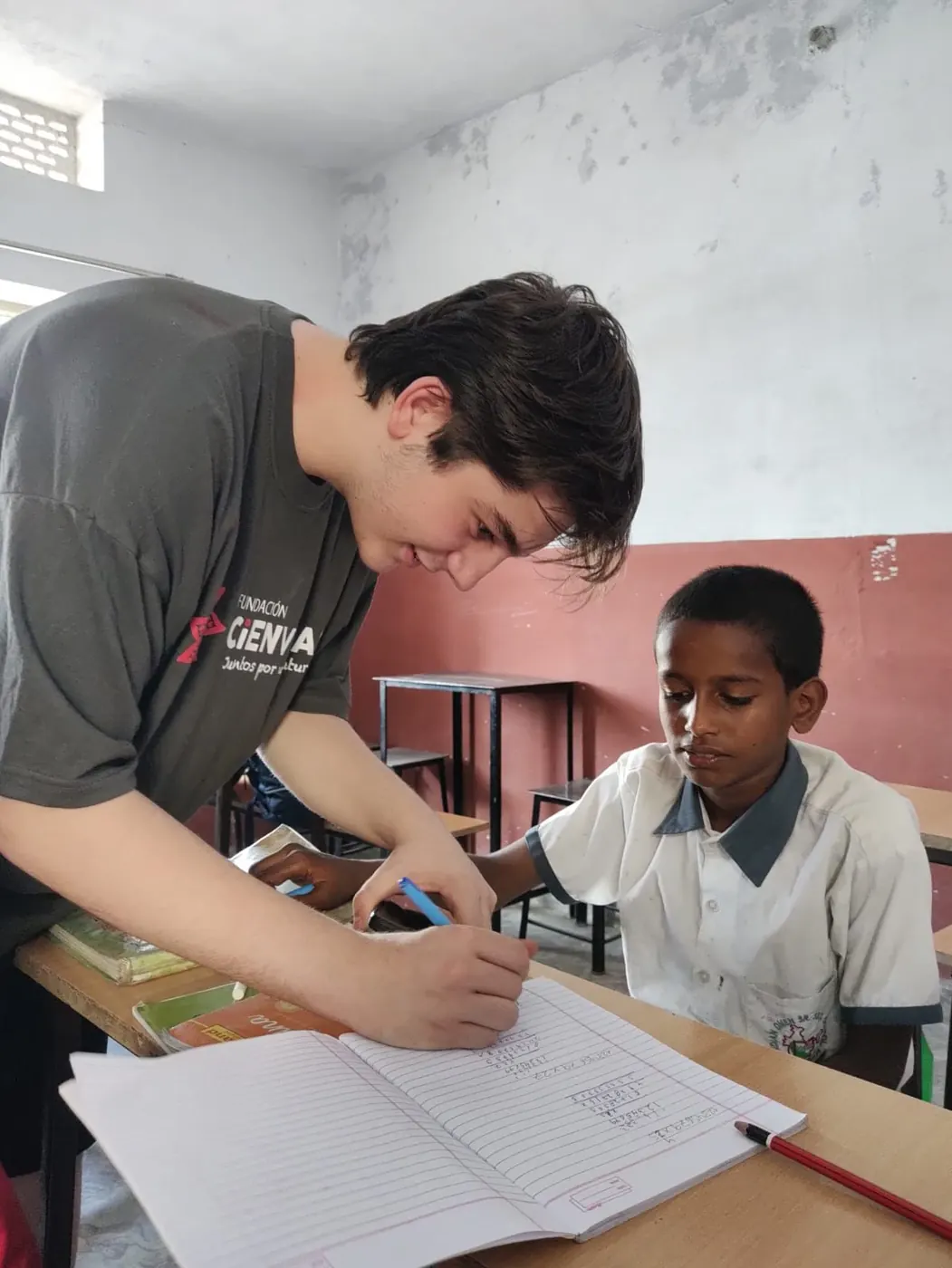 Volunteer giving a child school support in a classroom in India