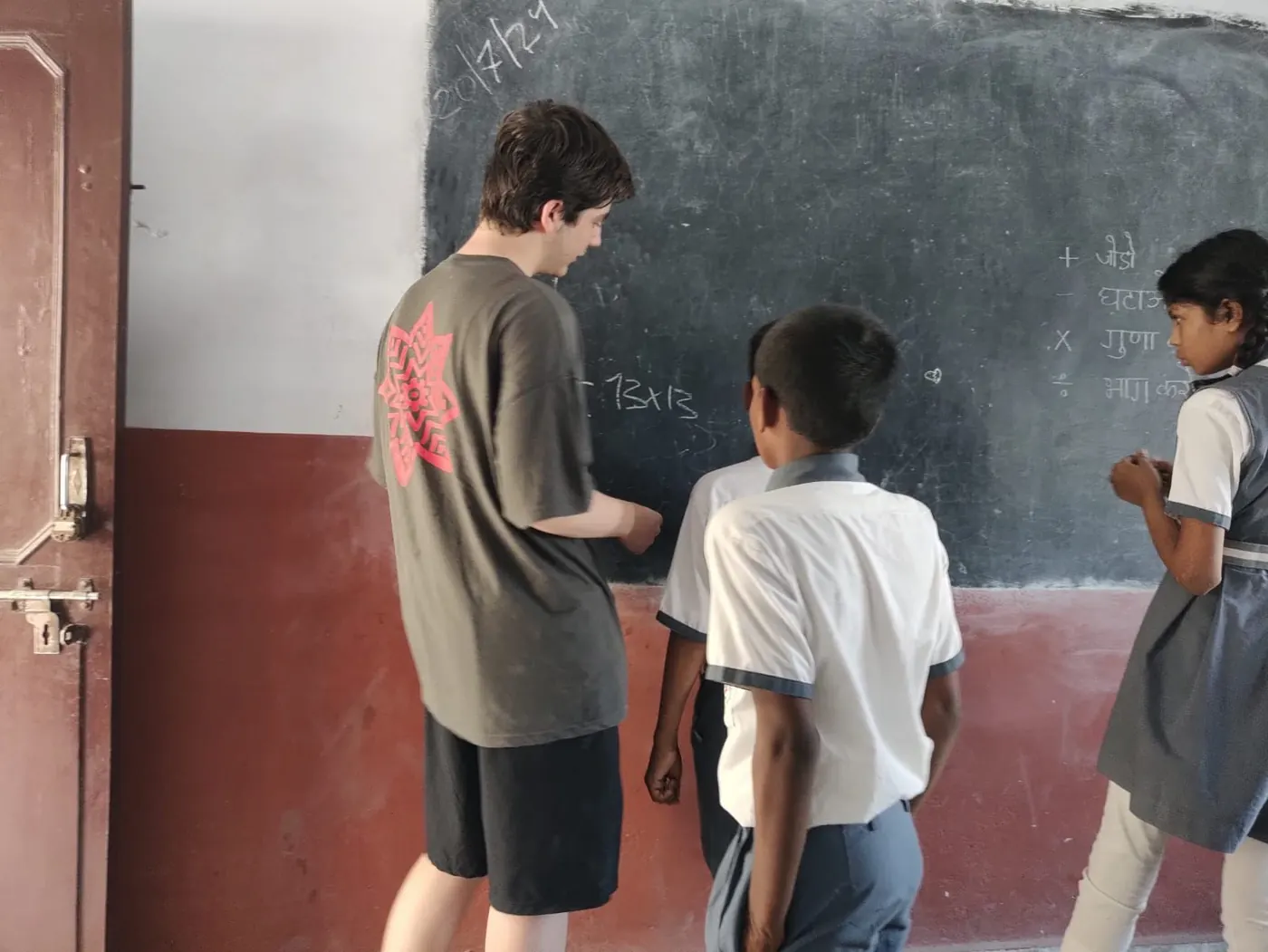 Volunteer teaching an English class on the blackboard at a school in India
